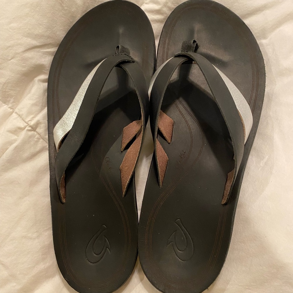 Olukai size 9 black leather flip flops with silver accent. Like new
